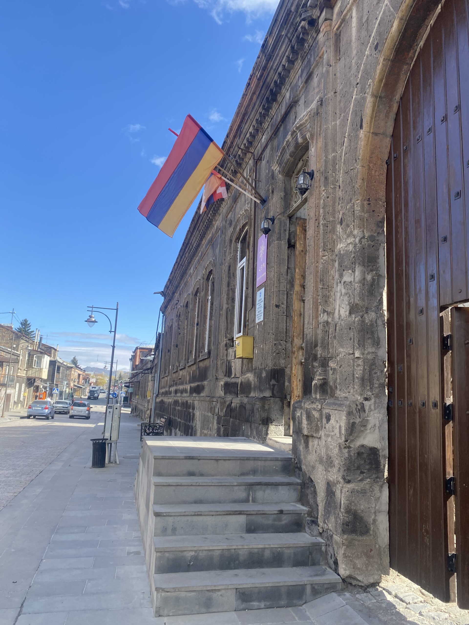 Carrer de pedra del centre de Gyumri amb la bandera armènia onejant a la façana