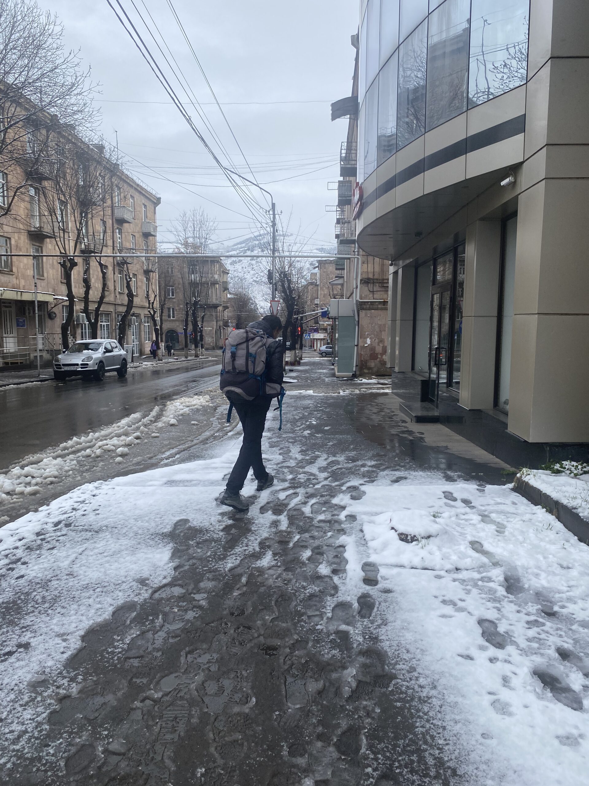 Carrer del centre de Vanadzor cobert de neu, amb un vianant caminant enmig del fred