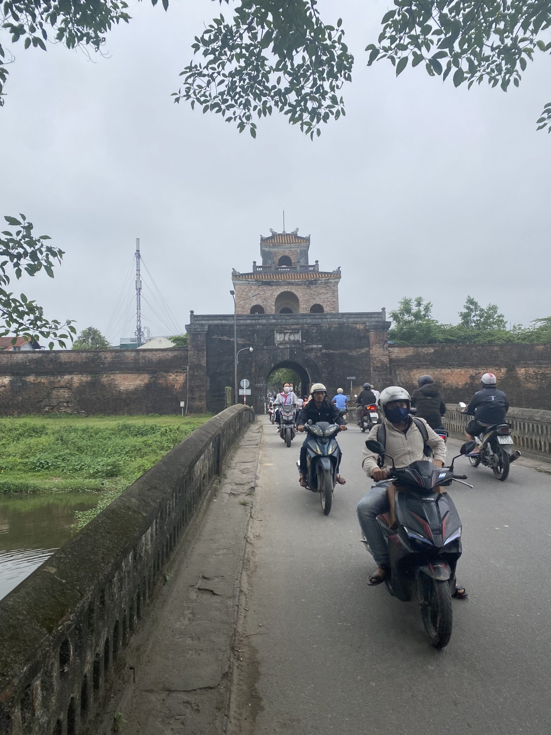 Porta fortificada amb fossat i motos travessant a la Ciutadella de Hue, Vietnam