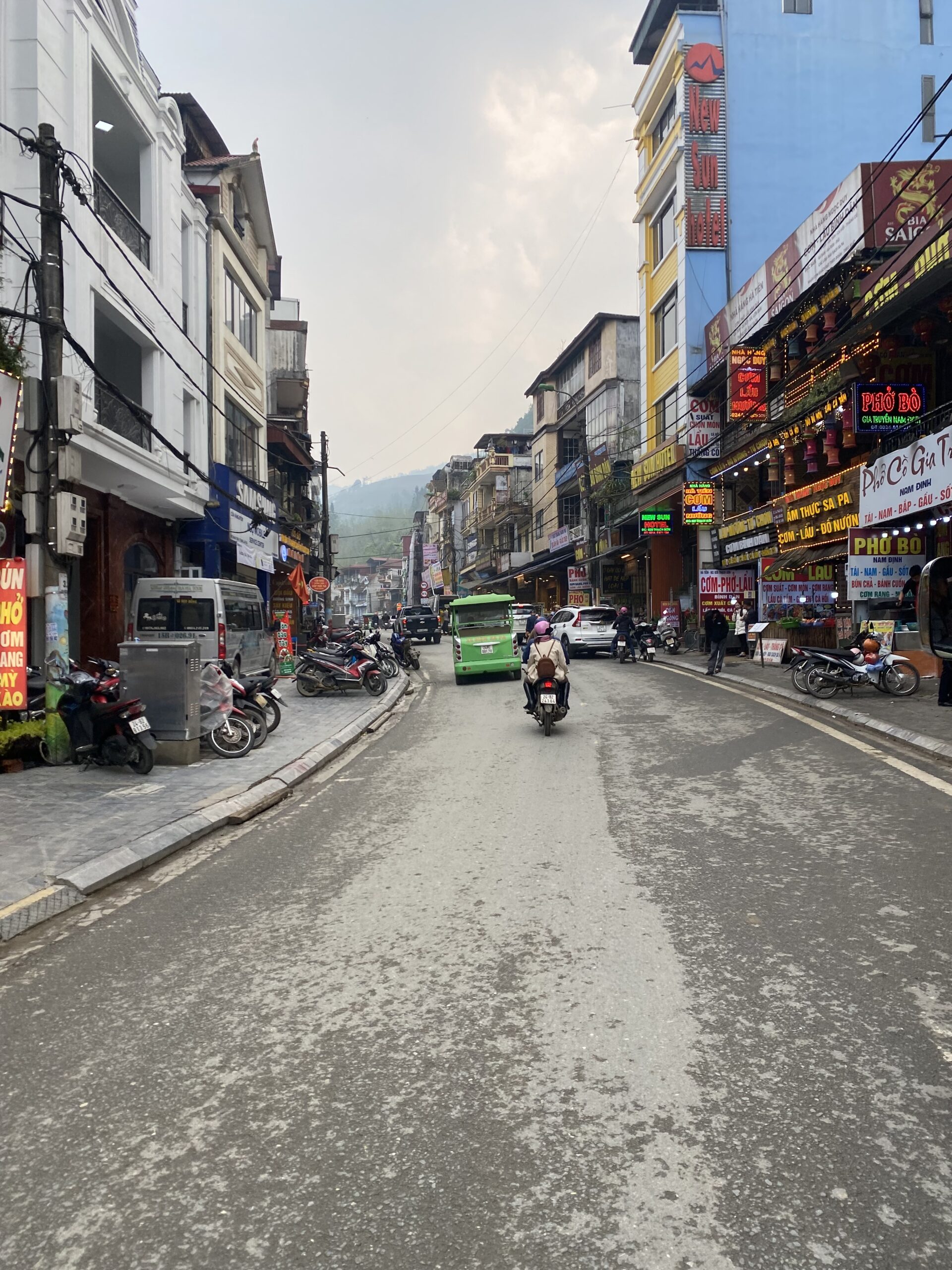 Carrer del poble de Sapa amb edificis i trànsit de motos, Vietnam