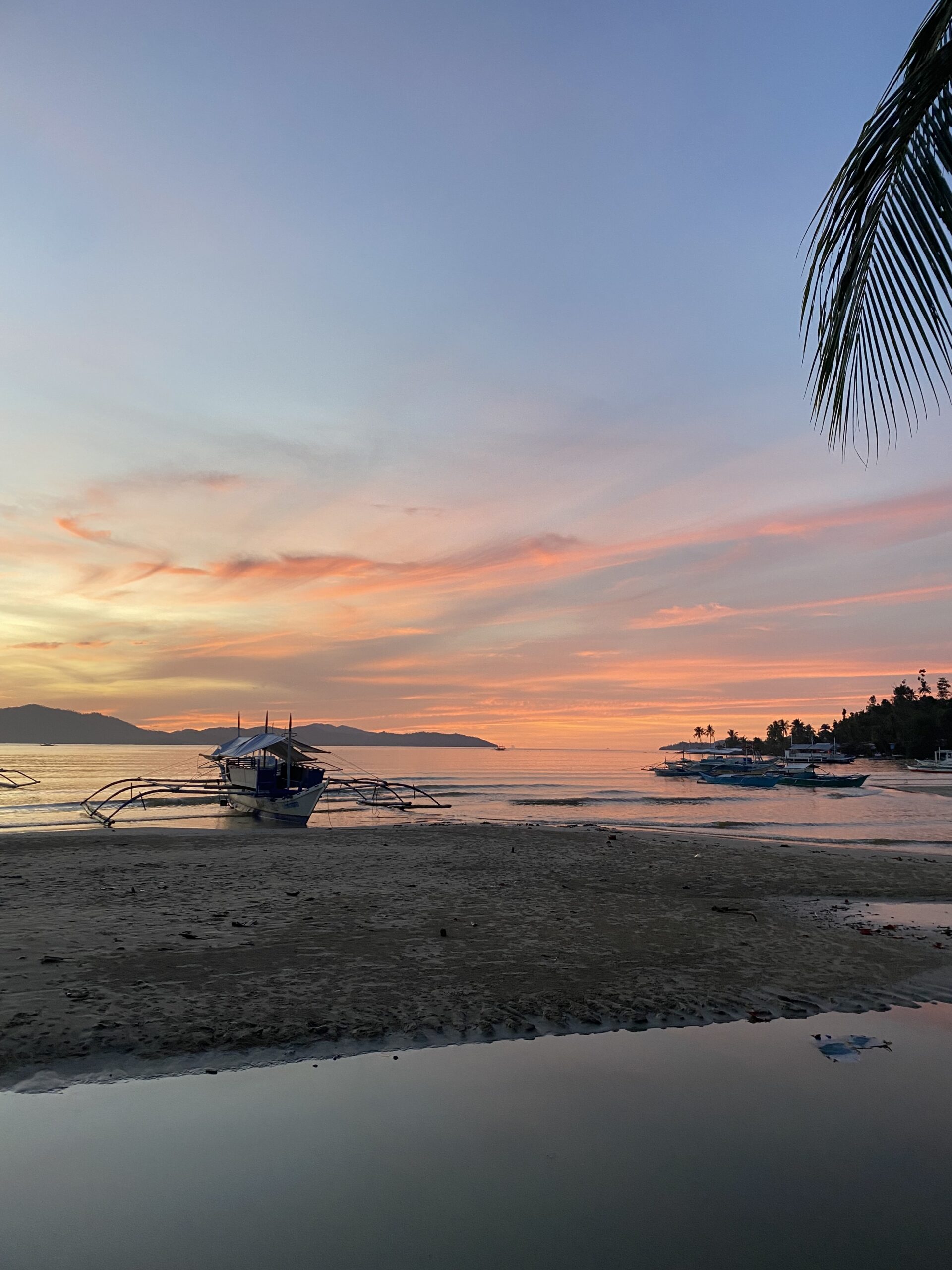 Capvespre de colors rosats amb barques davant la costa de Port Barton, Palawan.