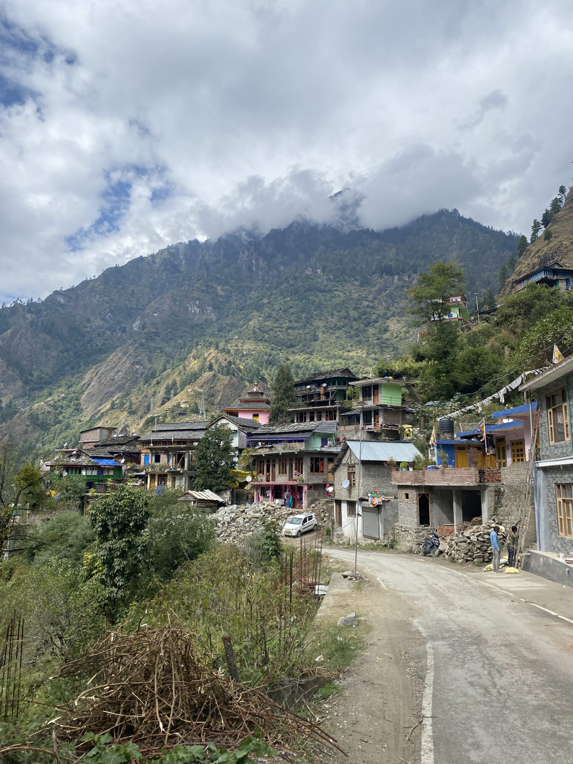 Cases de Kasol envoltades de boscos i muntanyes cobertes de núvols a la vall de Parvati, Índia.