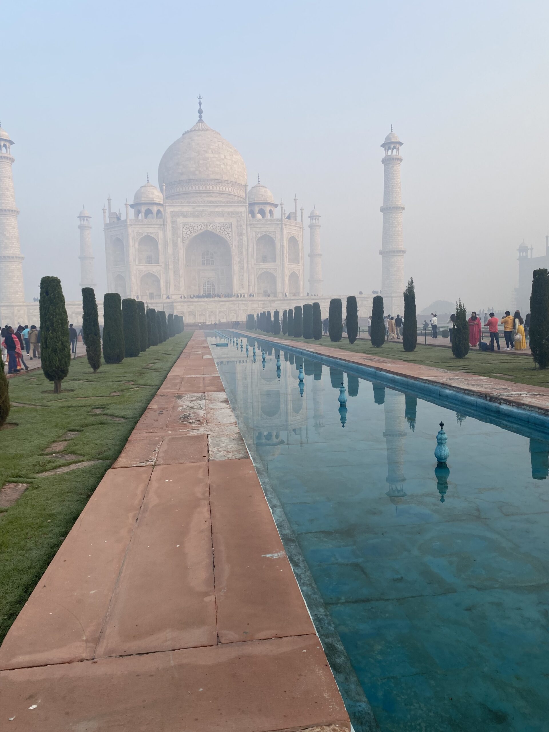 Taj Mahal reflectit al canal central dels jardins, amb xiprers i visitants, a Agra, Índia.