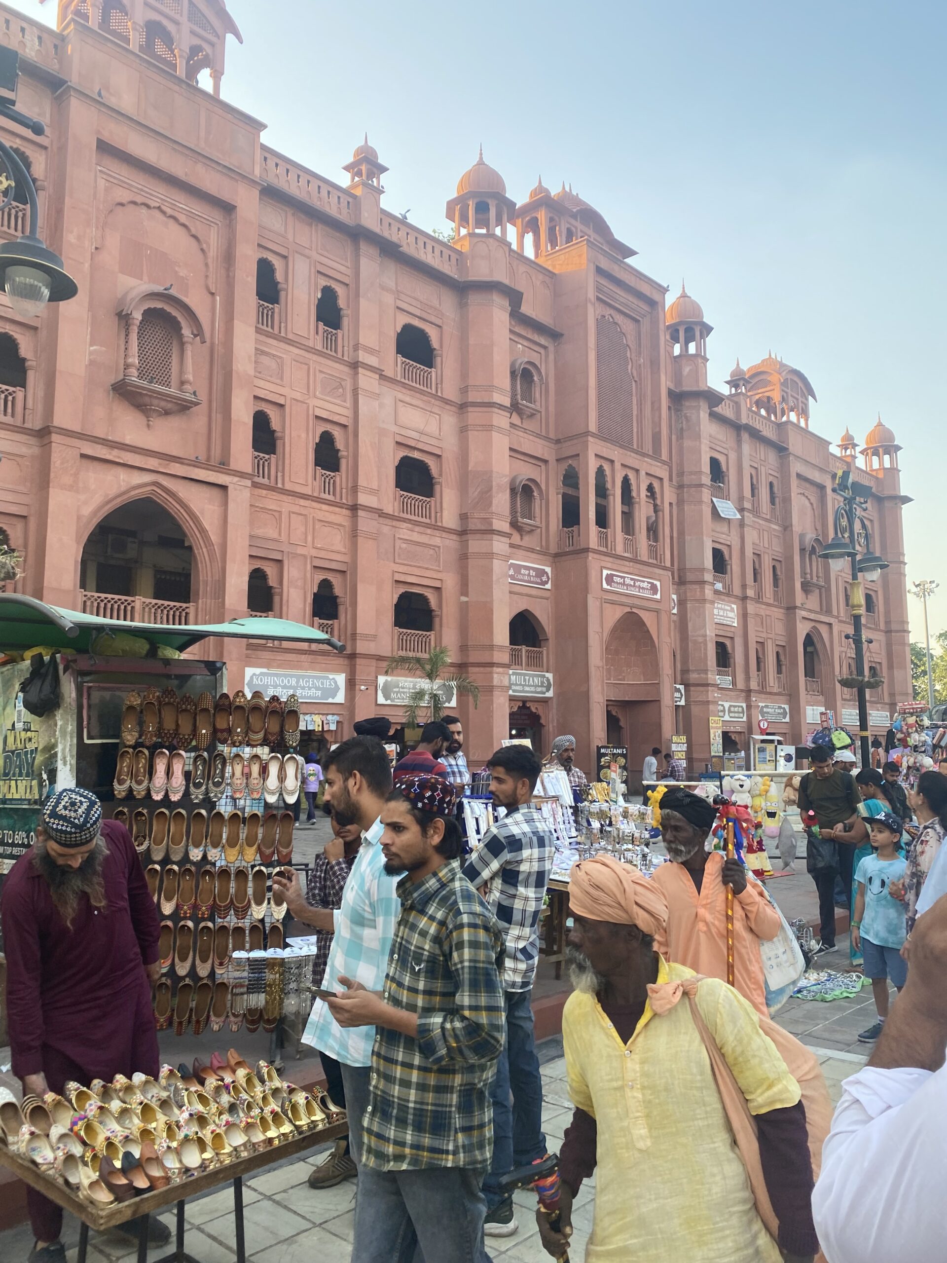 Edifici històric de façana rogenca envoltat de visitants al centre d'Amritsar, Índia.