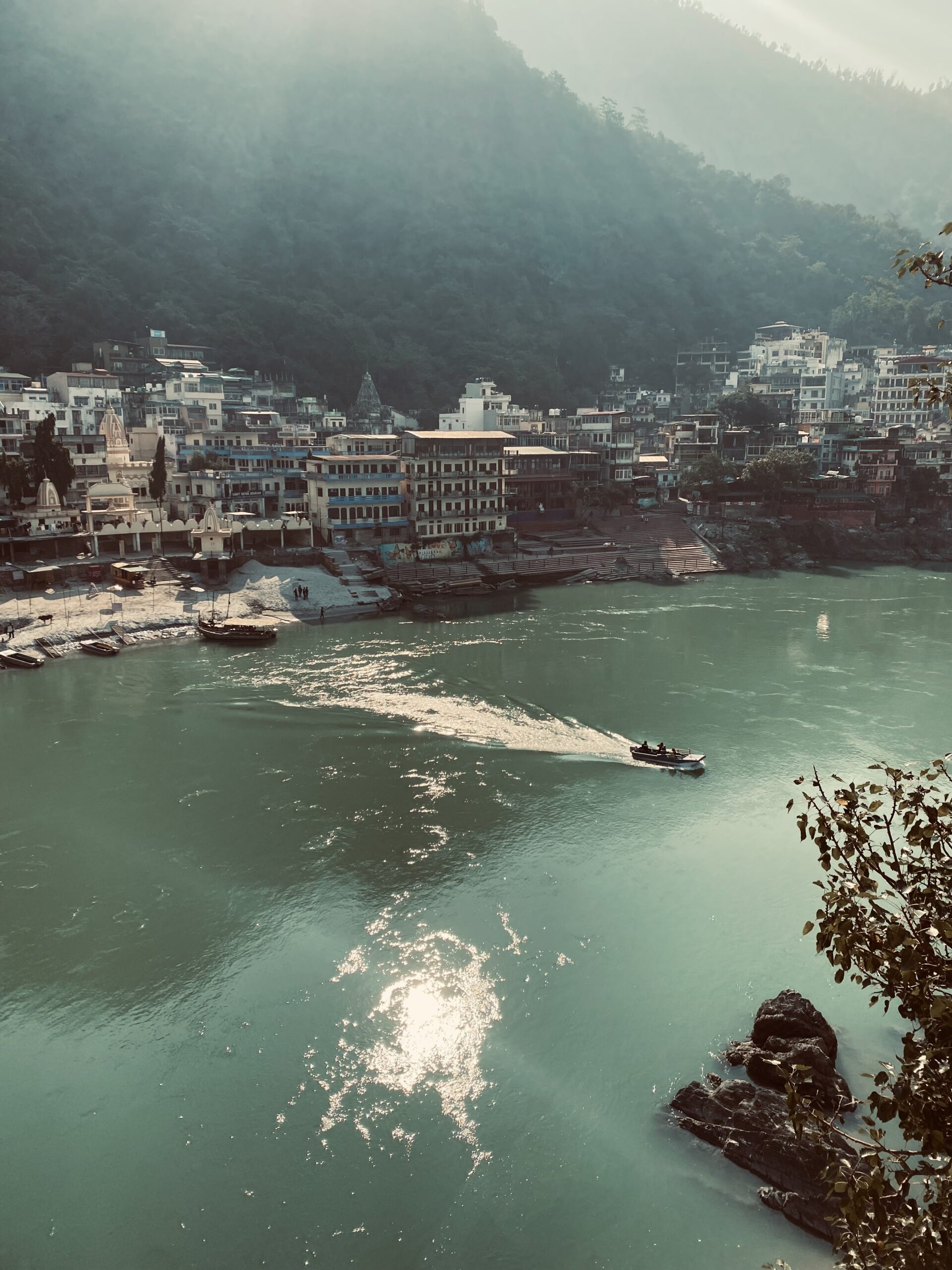 Barca navegant pel riu Ganges davant dels ghats i els edificis de Rishikesh, Índia.