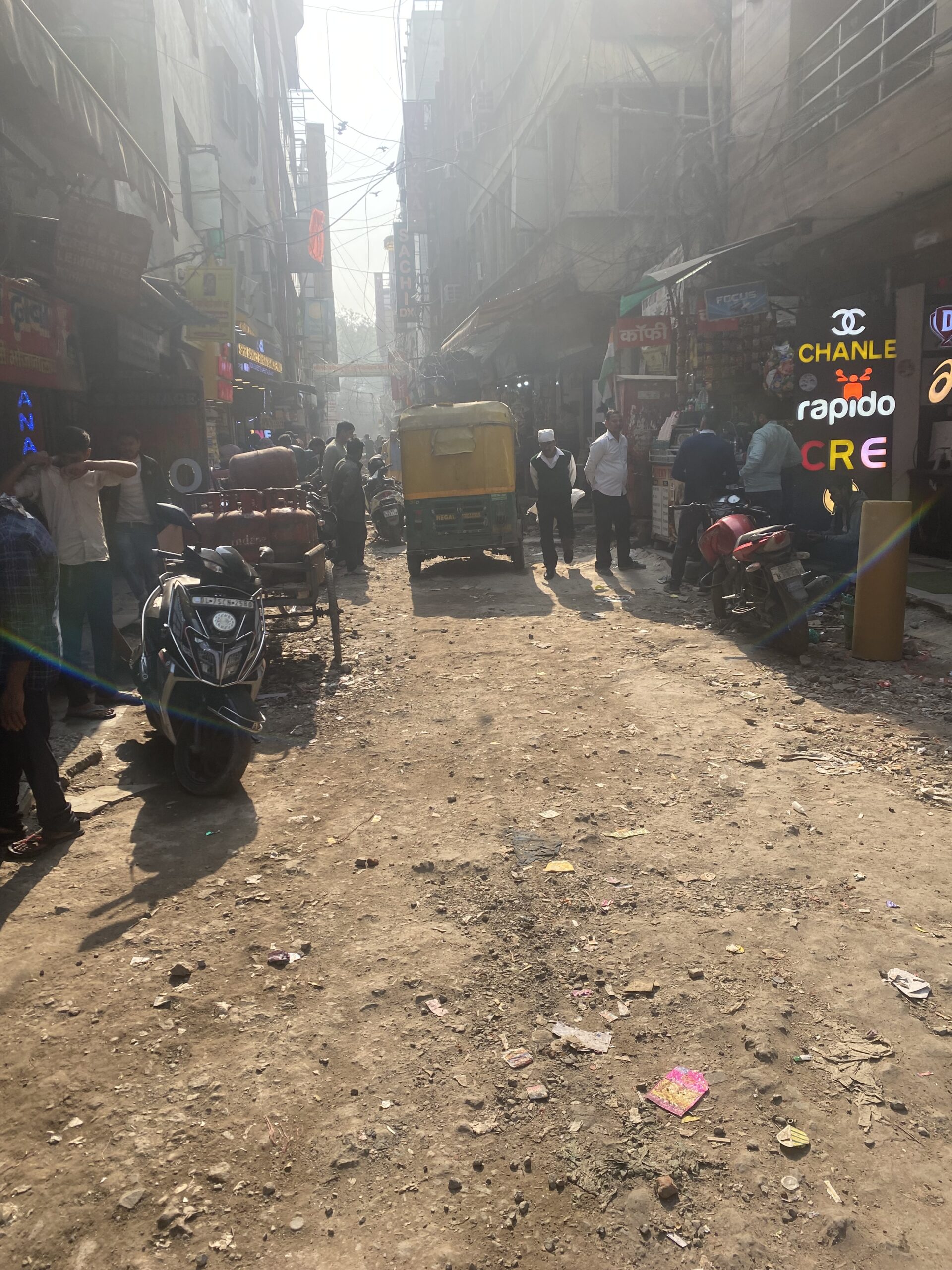 Carreró estret amb vianants, motos i petits comerços al centre històric d'Old Delhi, Índia
