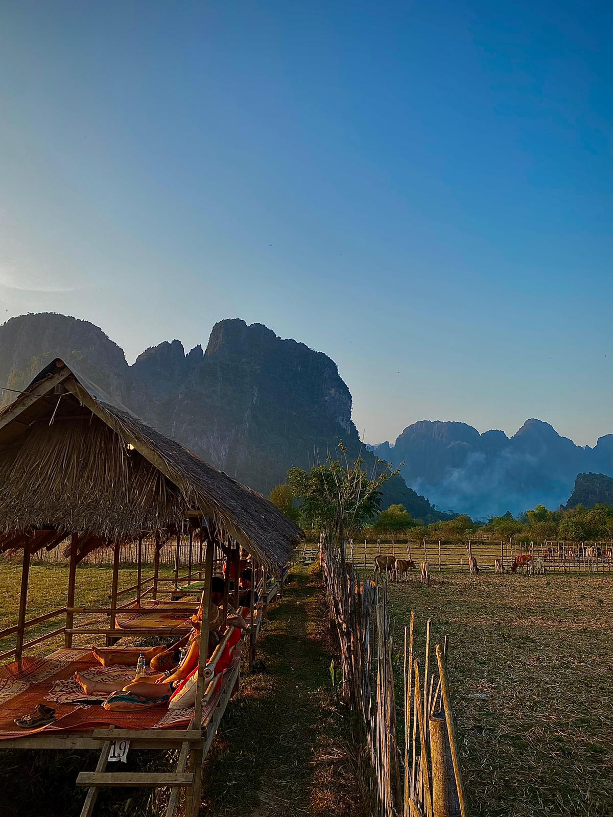 Teulada d'una cabana de bambú amb les muntanyes càrstiques de Vang Vieng al fons
