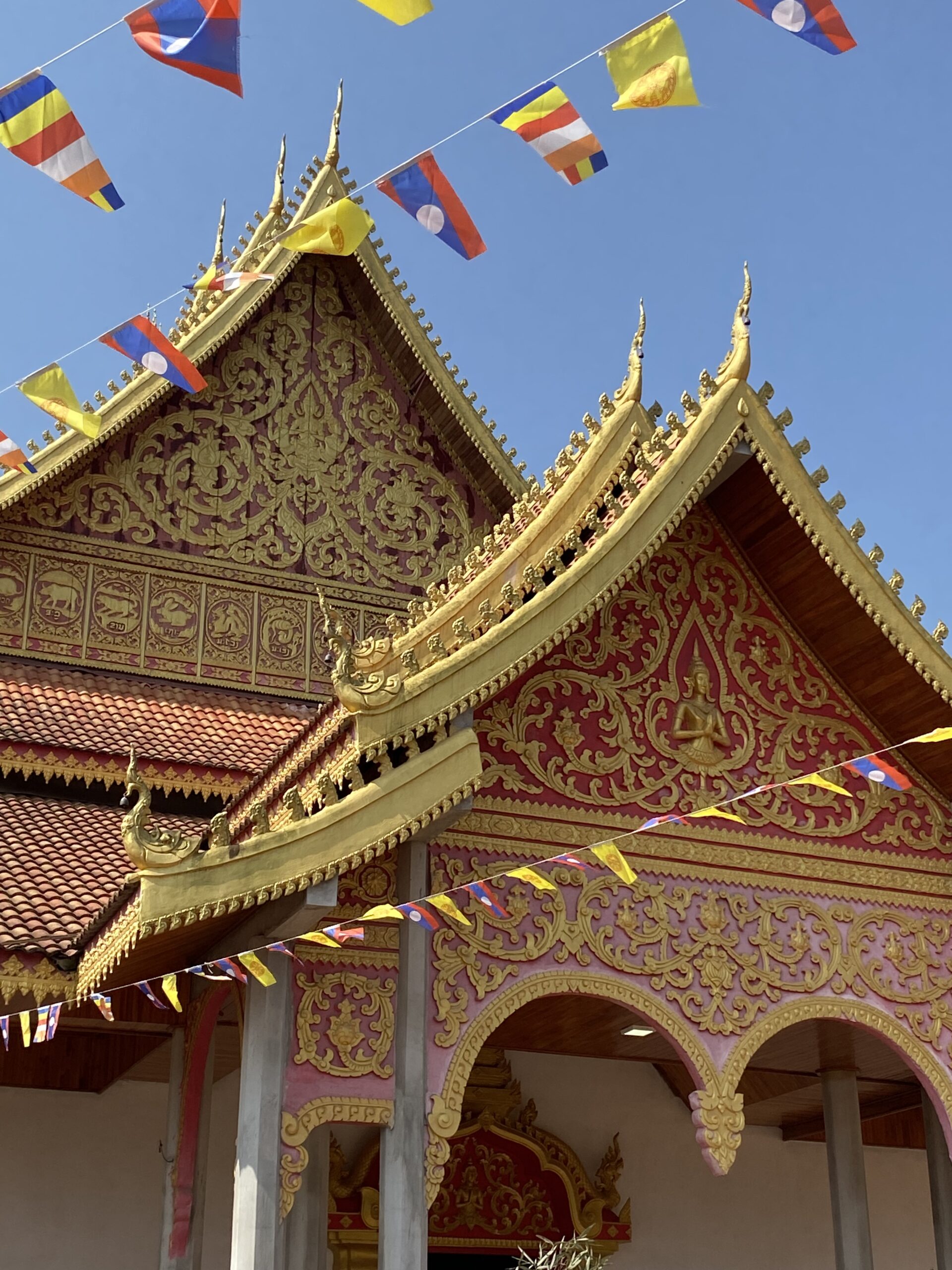 Teulades ornamentades d'un temple budista de Luang Namtha amb banderes de colors