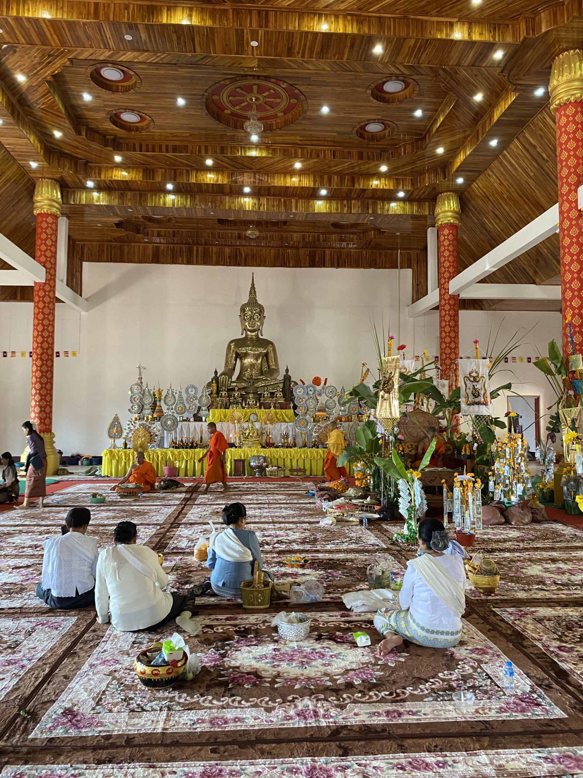 Interior d'un temple budista de Luang Namtha amb imatges de Buda i ofrenes