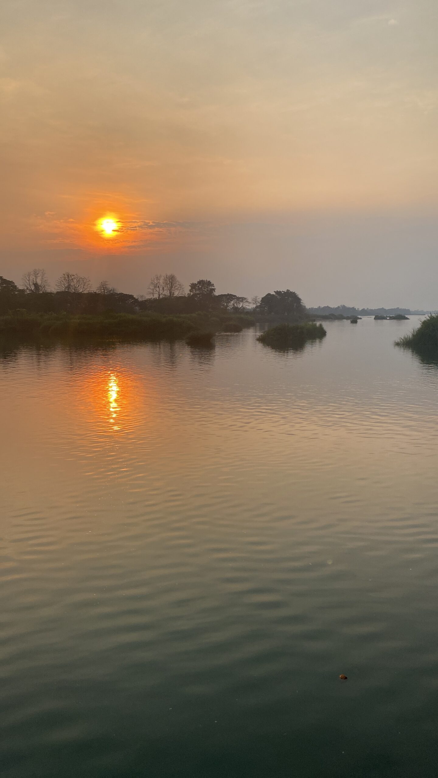 Sol taronja reflectit al Mekong entre la calitja a Don Det
