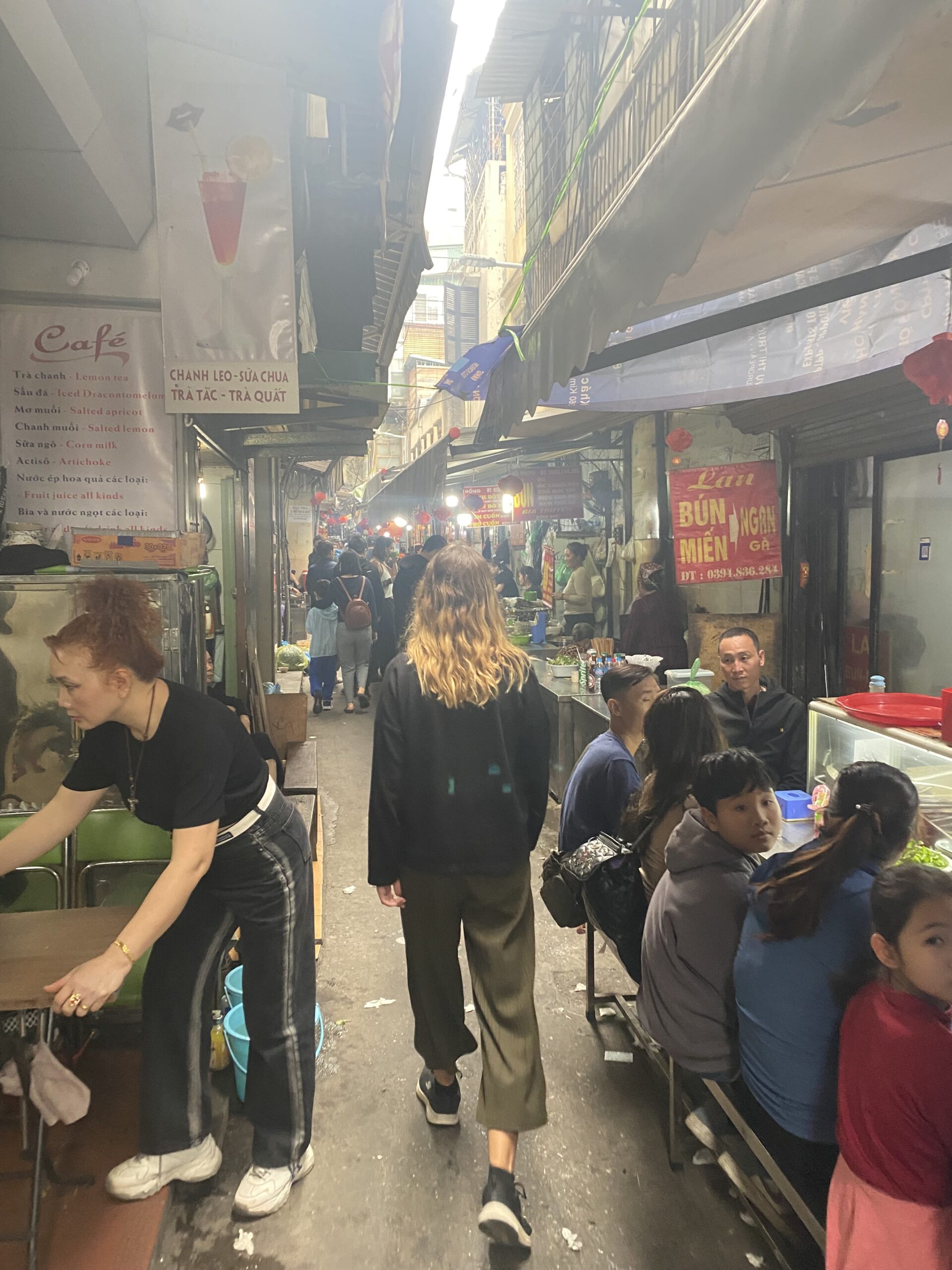 Carrer estret del barri antic de Hanoi ple de parades de mercat i gent comprant