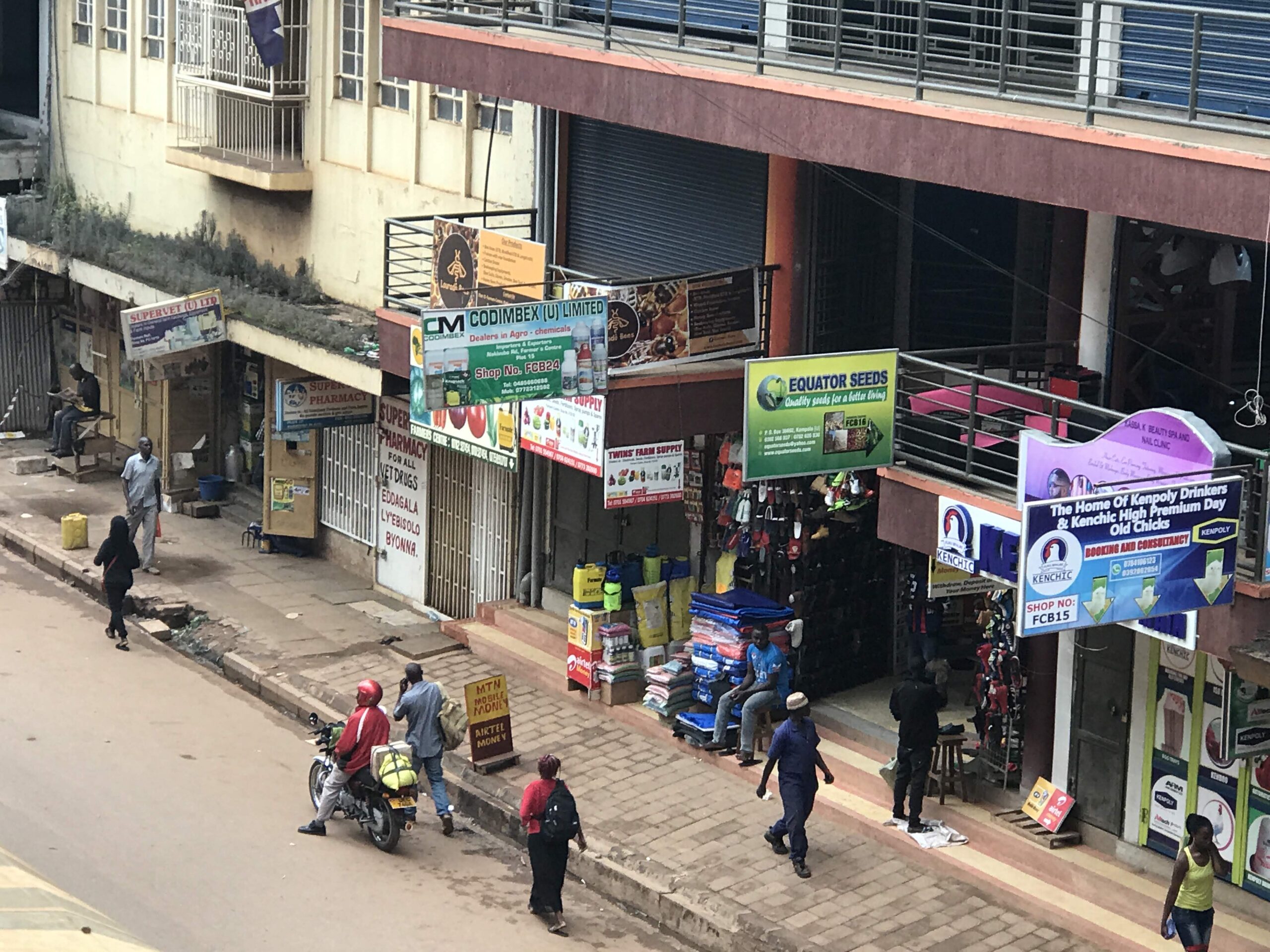 Carrer comercial del centre de Kampala amb vianants, botigues i rètols publicitaris