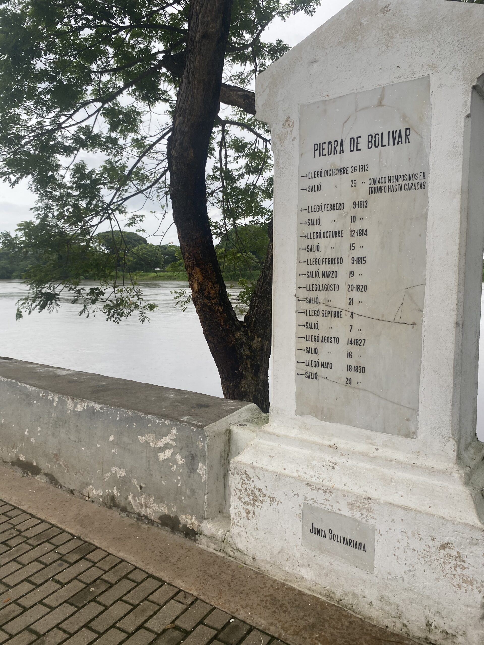 Monument de pedra amb una inscripció al costat d'un arbre i del riu Magdalena a Mompox