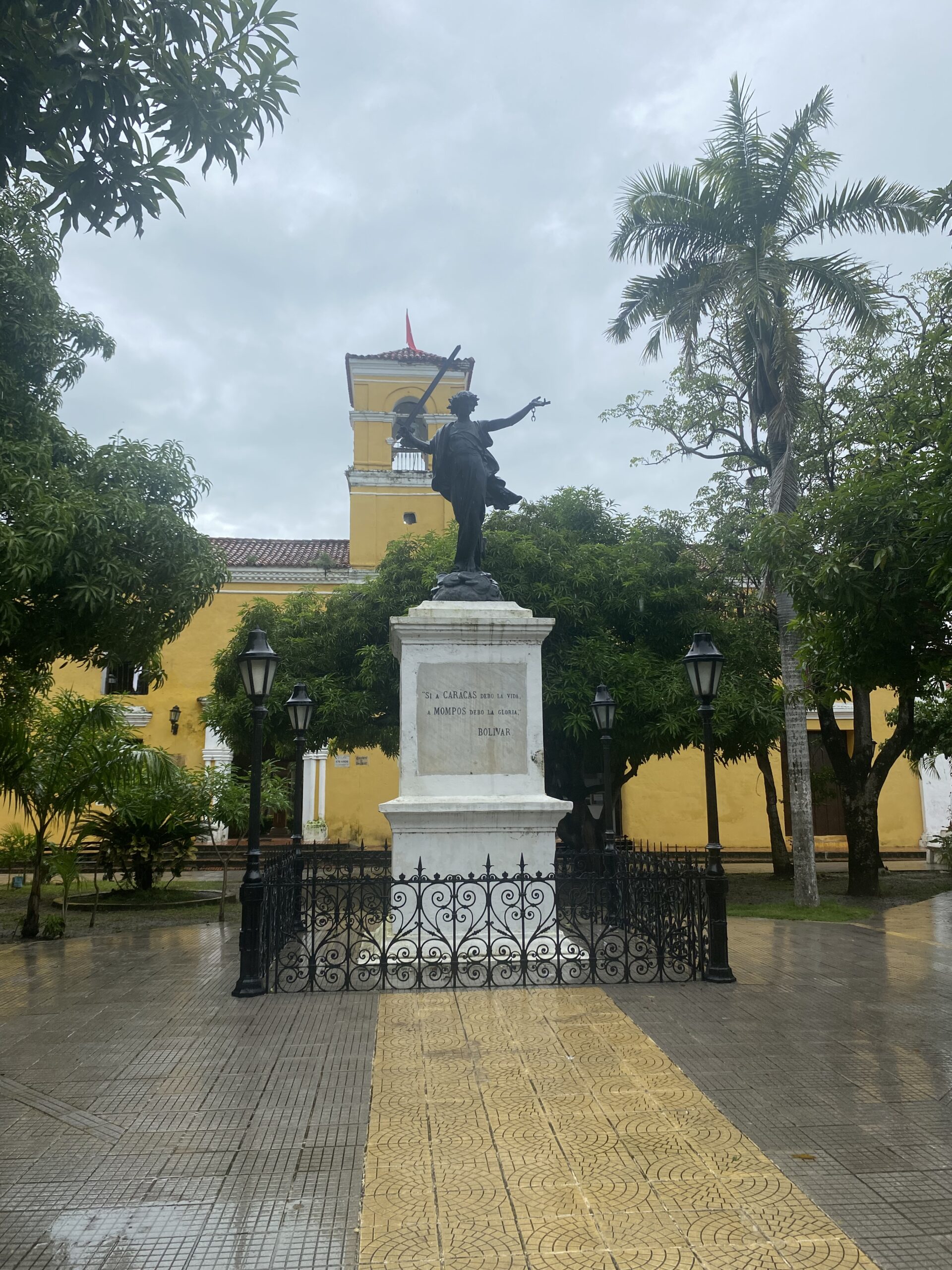 Monument amb un bust sobre un pedestal en una plaça arbrada de Mompox
