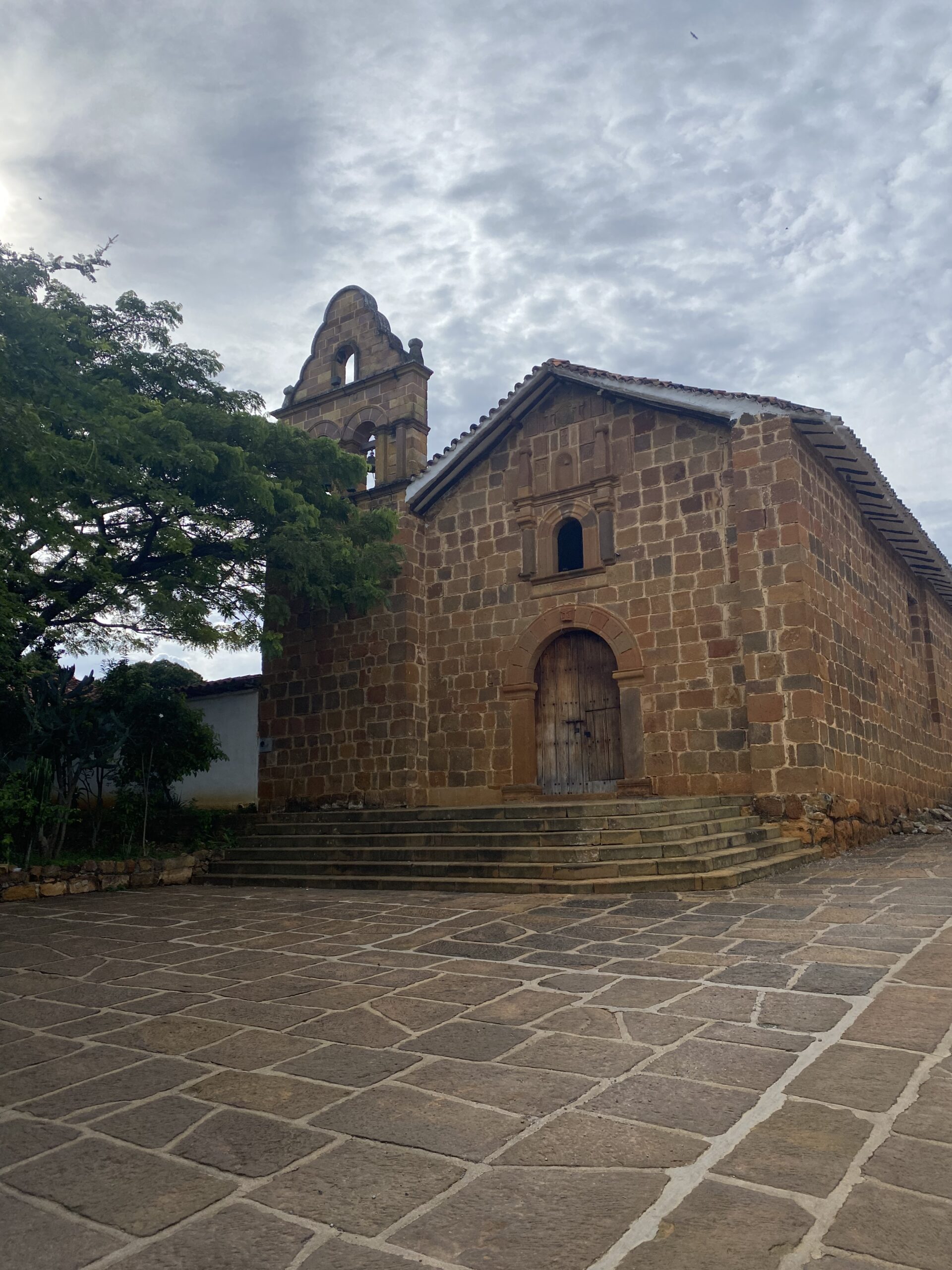 Construcció de pedra amb teulada de teula entre la vegetació de Barichara