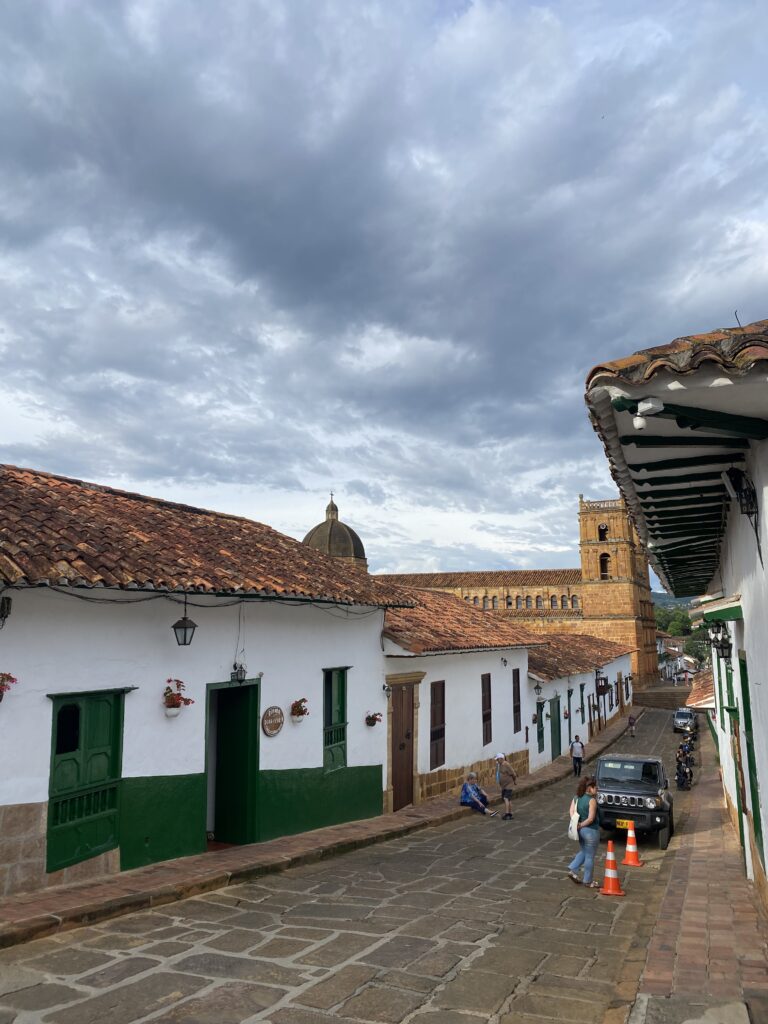Carrer empedrat de Barichara amb cases blanques, teulades de teula i cel ennuvolat.