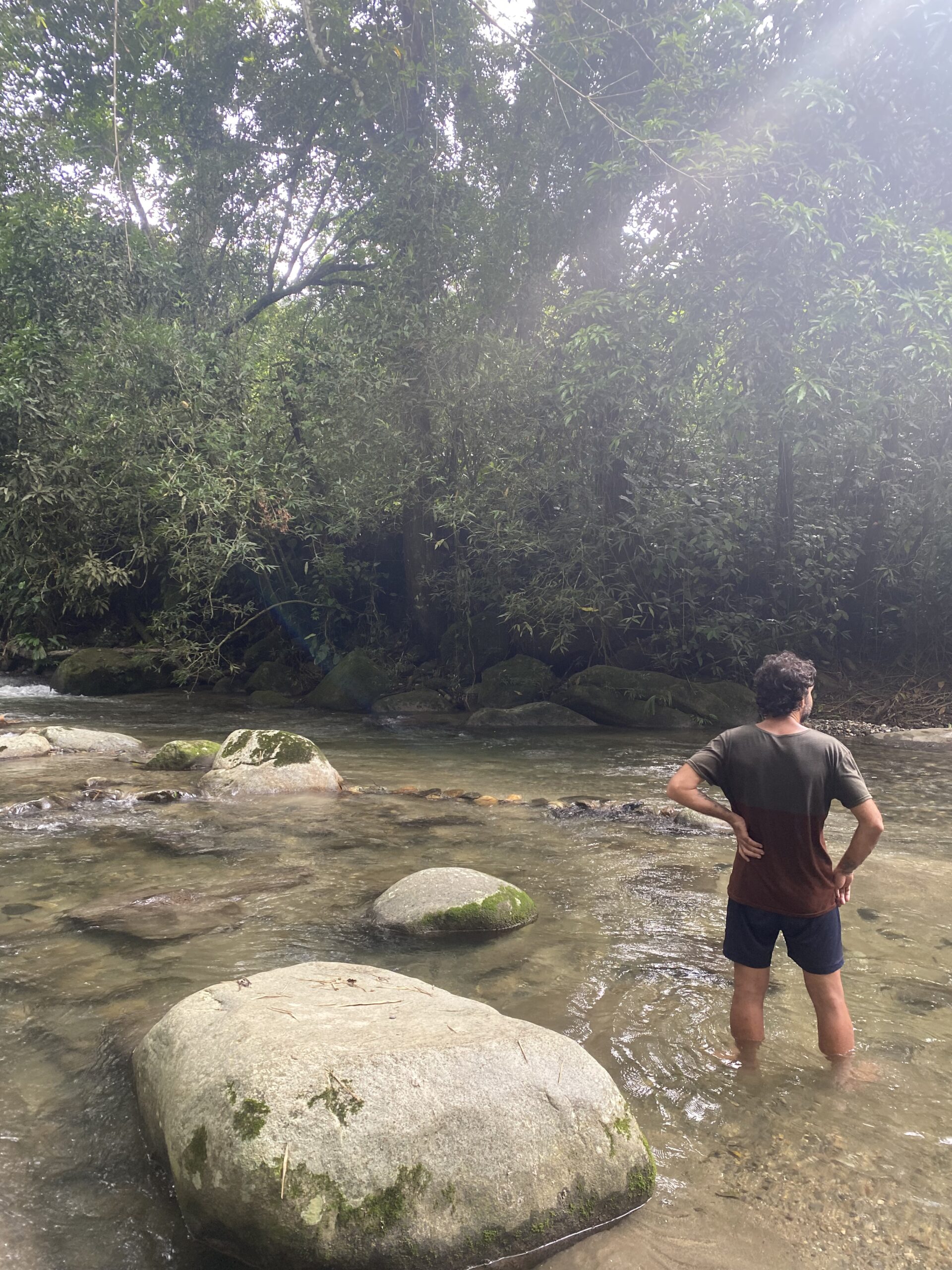 Fent una parada a la vora d'un riu ple de roques, envoltat de selva, durant una caminada als voltants de Minca