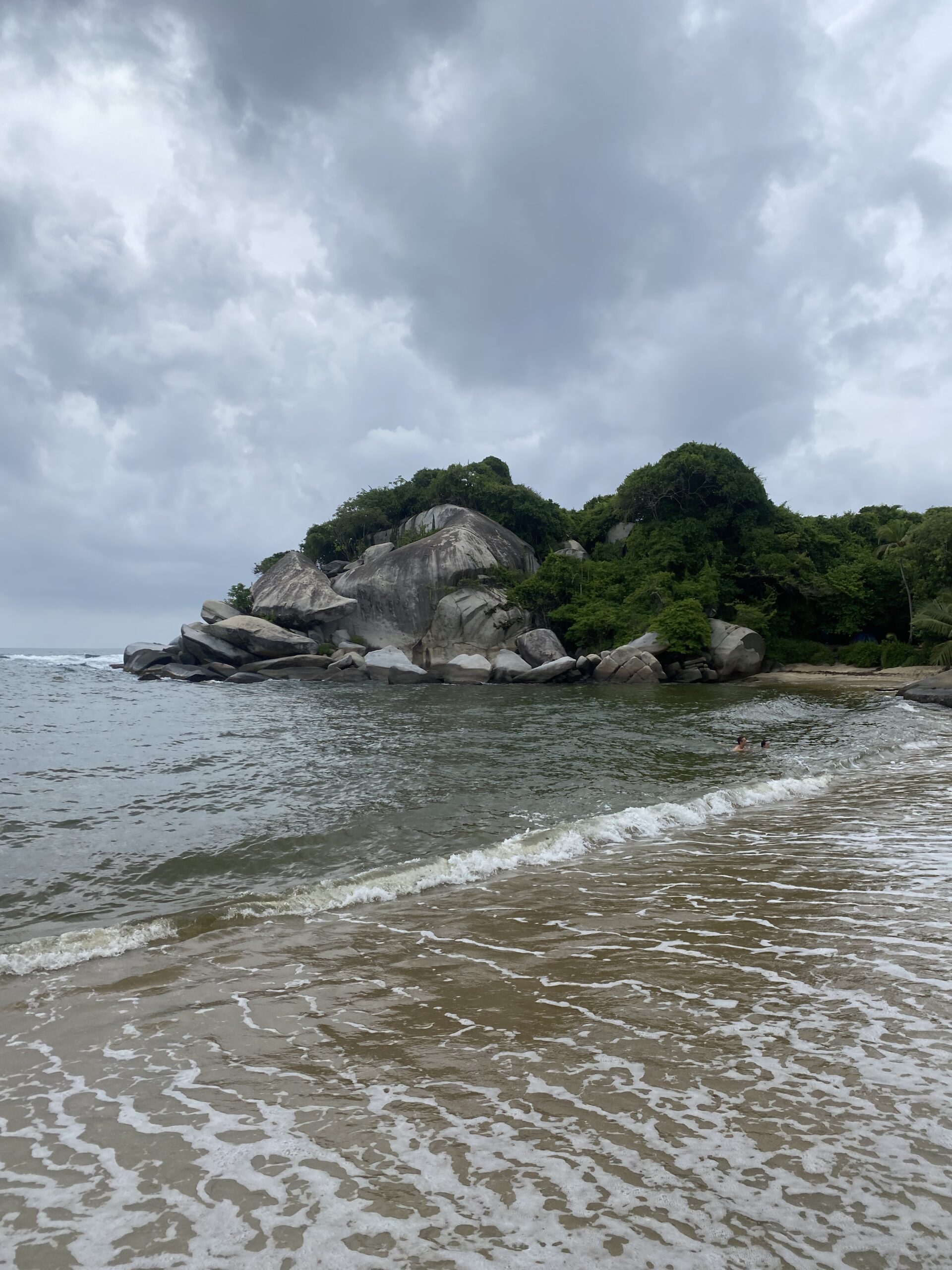 Roques granítiques cobertes de vegetació a la costa del Parc Tayrona, davant del mar Carib