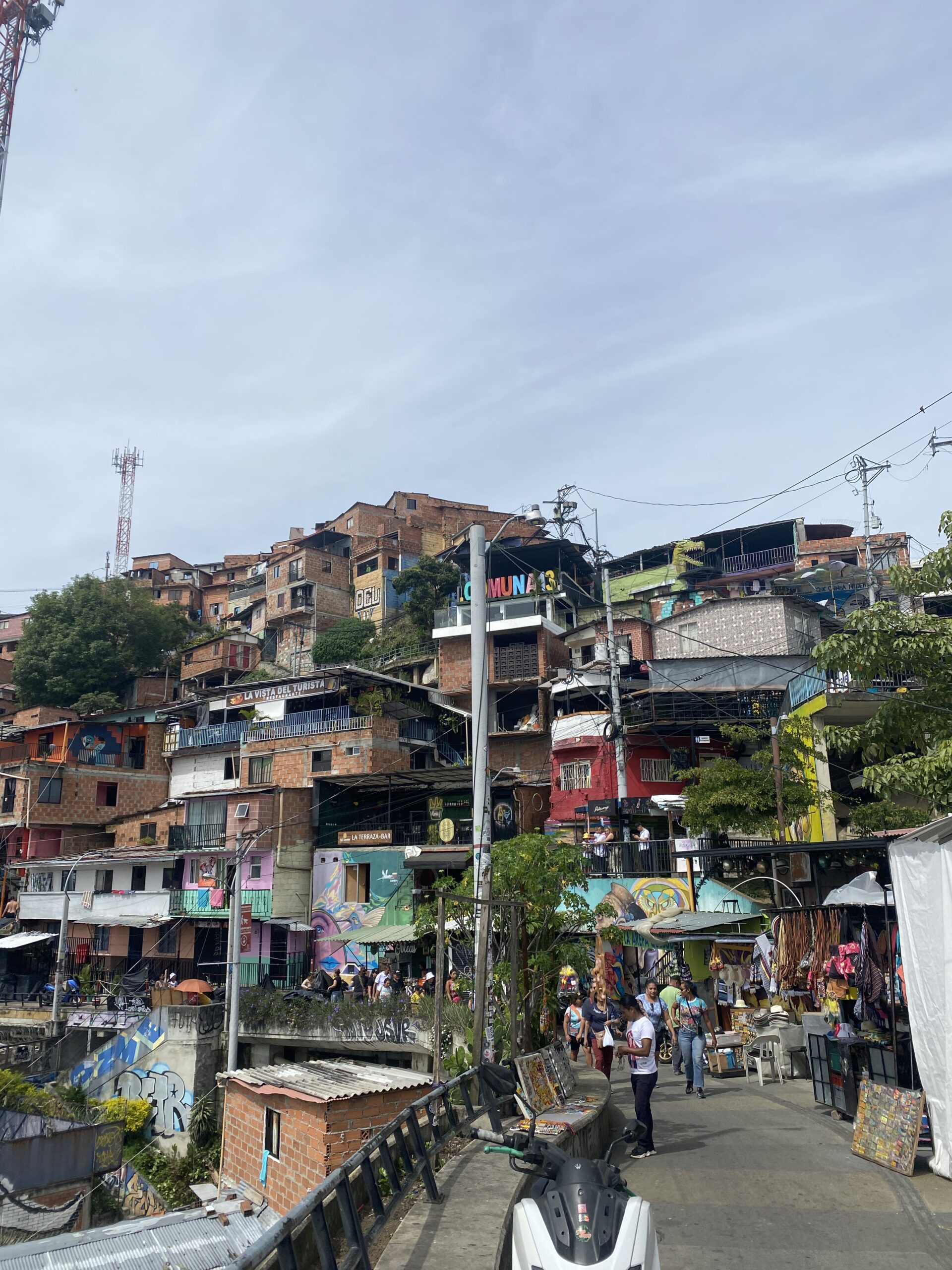 Cases de maó i de colors de la Comuna 13 de Medellín, amb el rètol del barri, murals i terrasses de bars