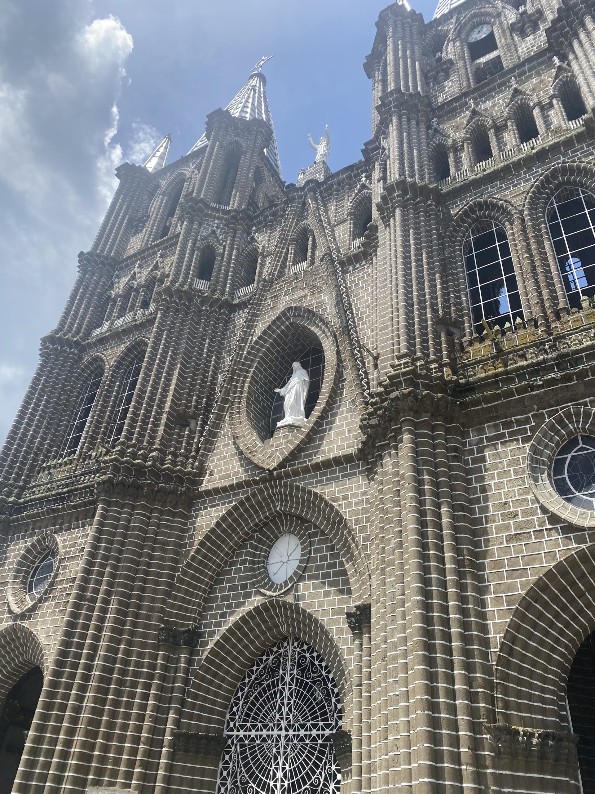 Façana de pedra neogòtica de la basílica de Jardín, amb el campanar i el cel blau