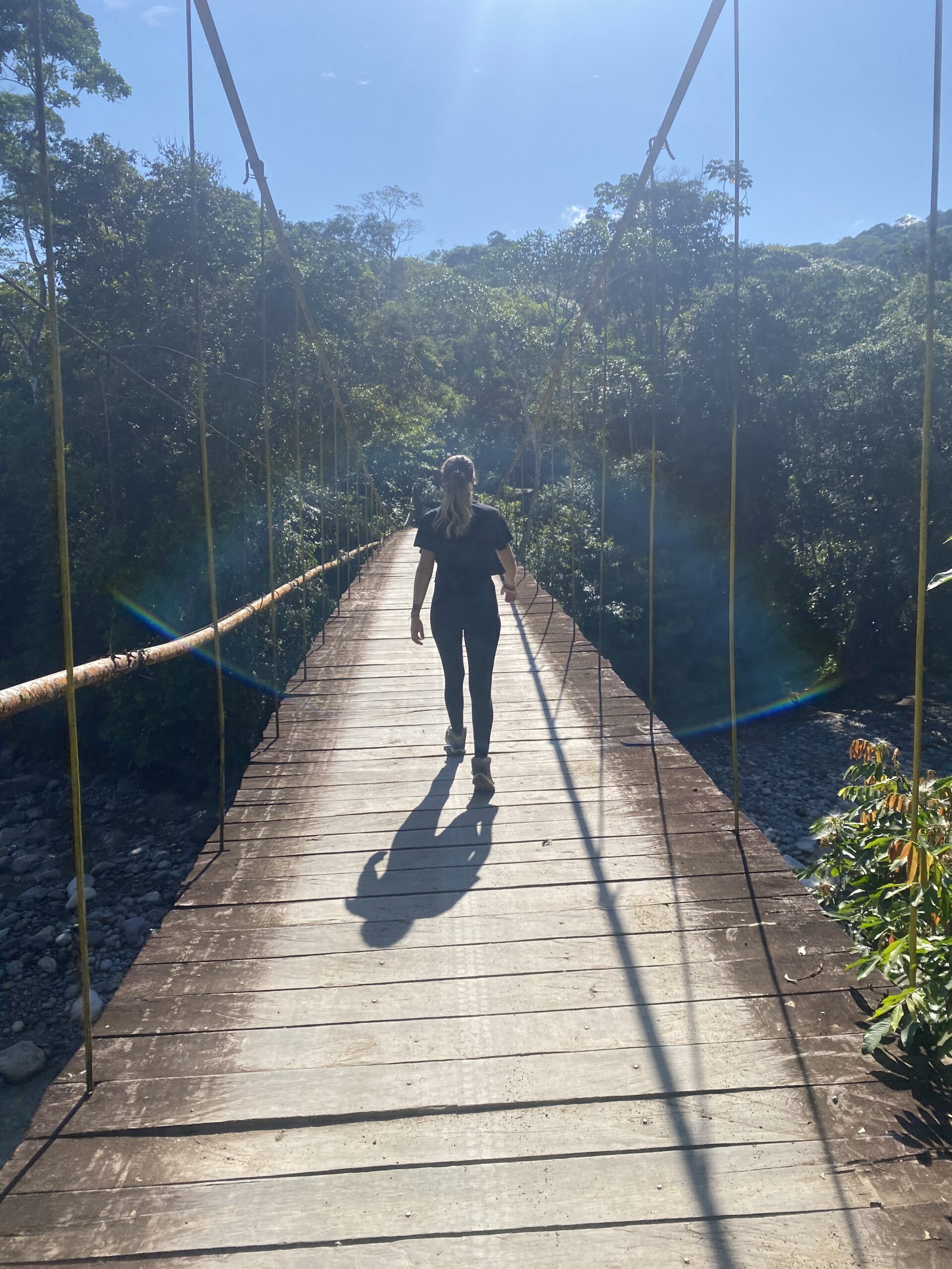 Creuant un pont penjant de fusta sobre el riu, envoltat de selva, a Mocoa