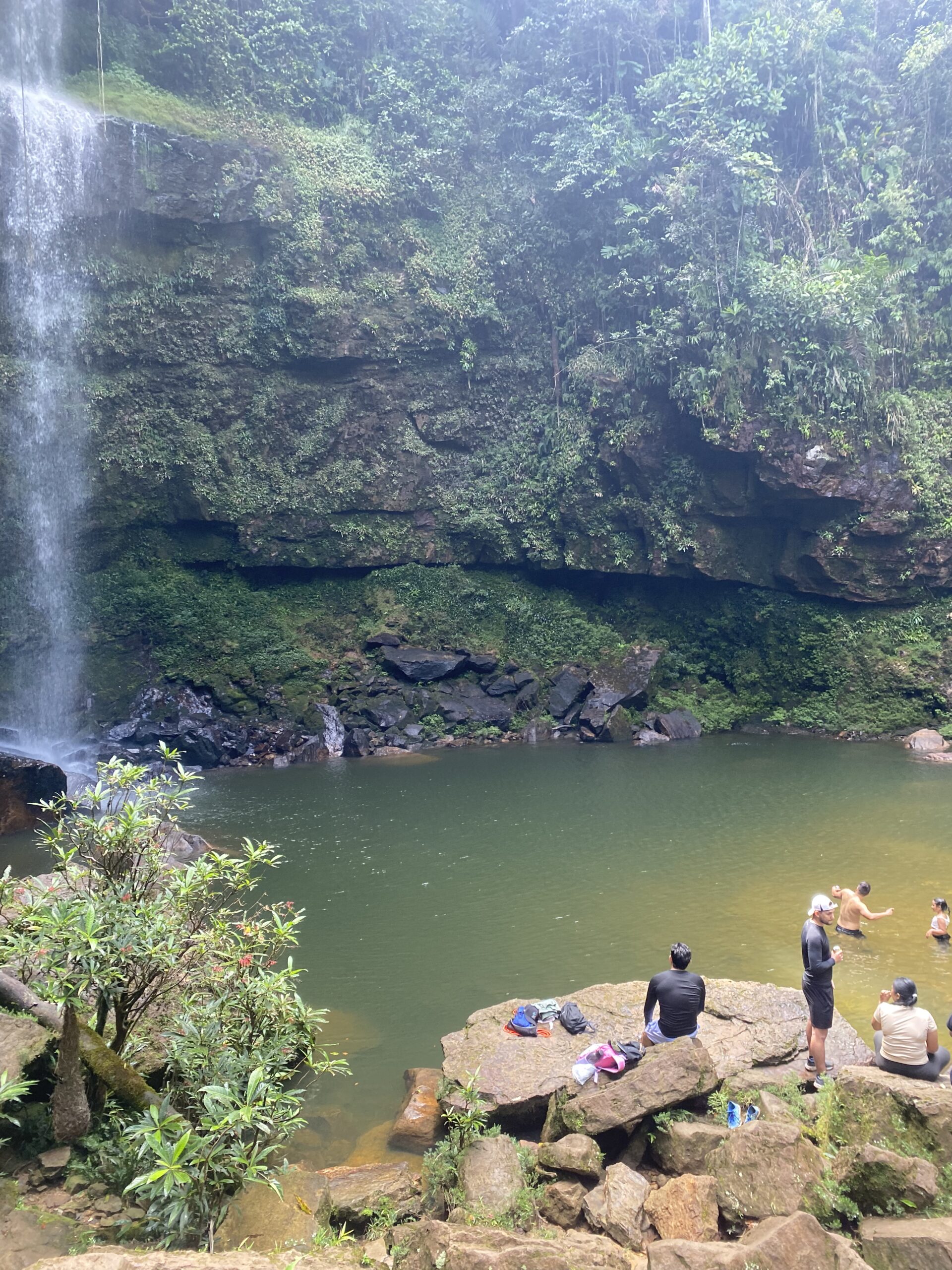 Gorg d'aigua verda a la base d'una cascada, envoltat de roca i vegetació, a Mocoa