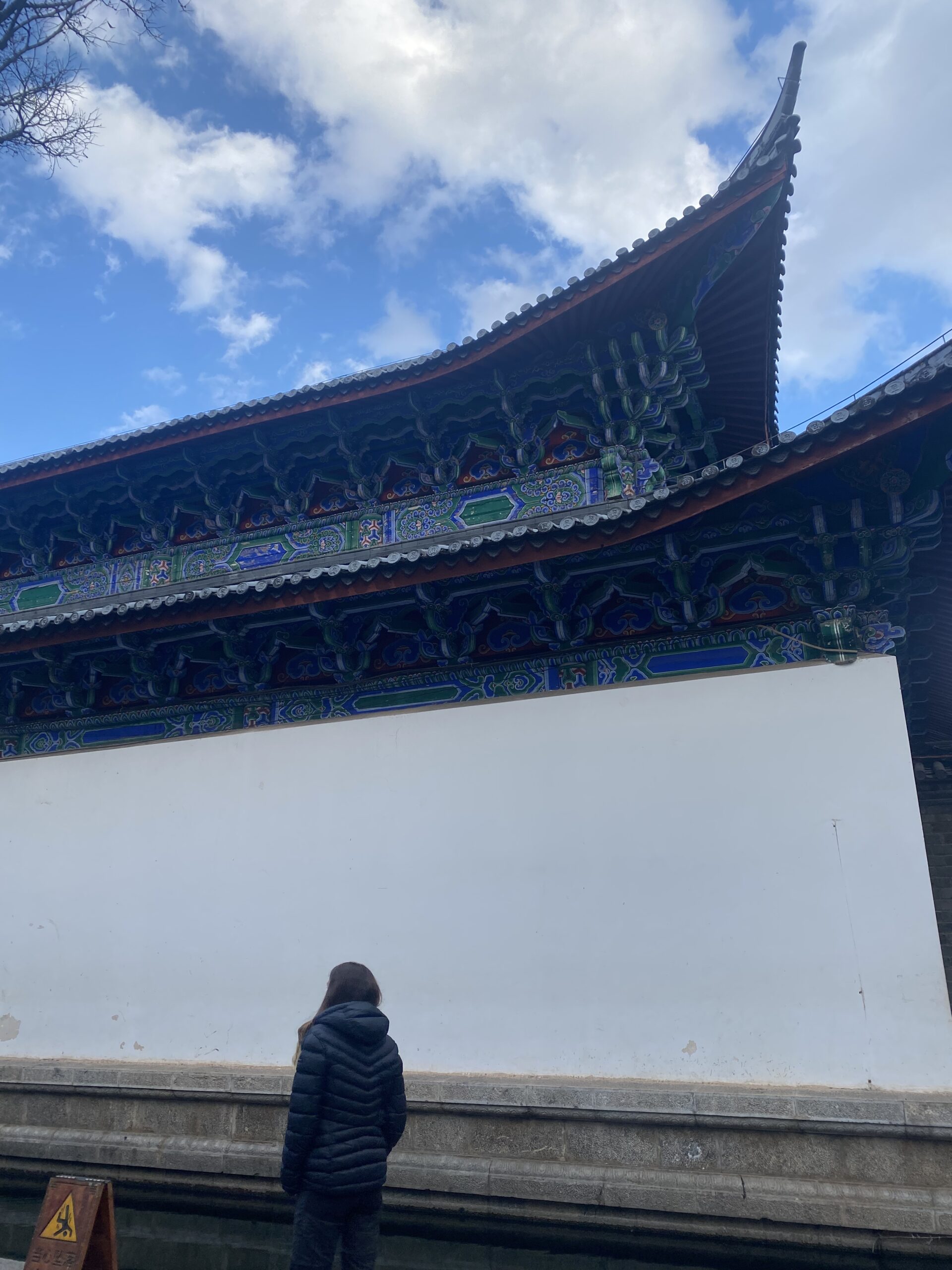Teulades corbades d'un edifici tradicional sota el cel blau de Lijiang