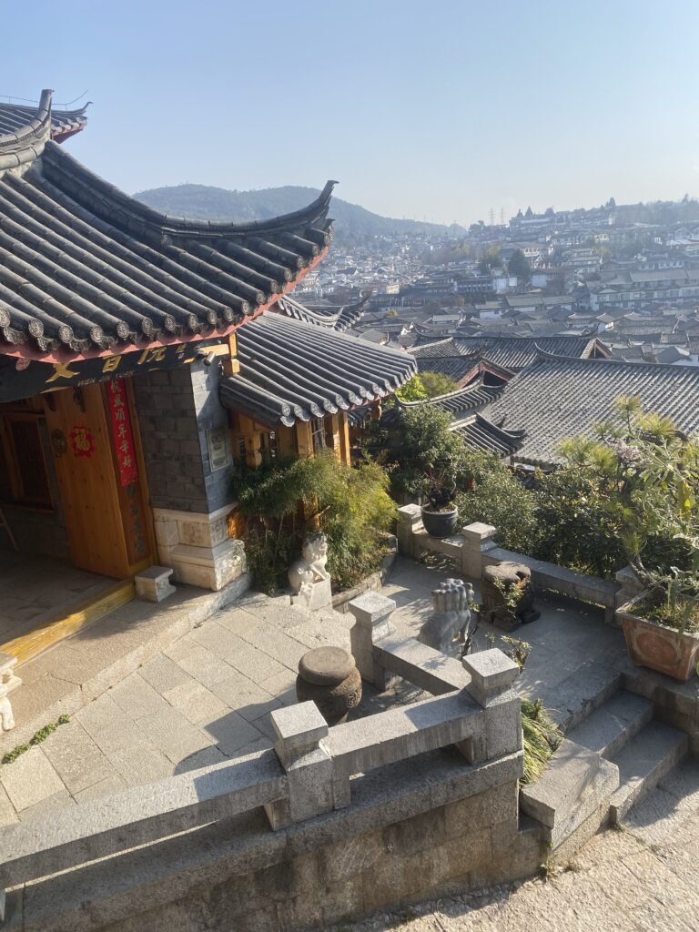 Pati de pedra i teulades corbades d’estil xinès amb vistes panoràmiques sobre Kunming.
