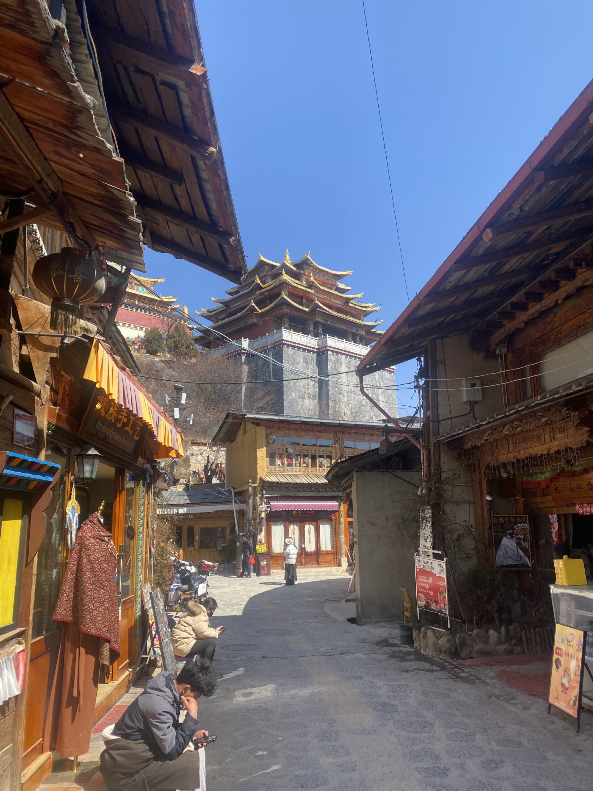 Carrer estret de la ciutat vella de Dukezong amb edificis de fusta tibetans sota el sol