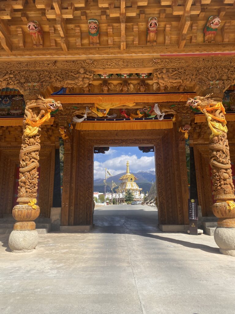Portal de fusta tallada amb vistes al recinte budista del monestir Sangpiling de Xiangcheng.