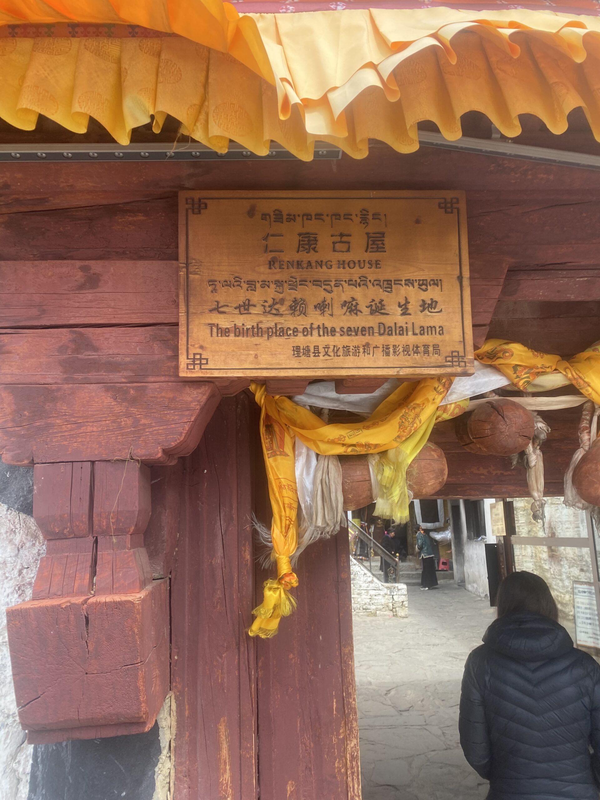 Placa amb inscripcions i bufandes khata a l'entrada d'un edifici històric de Litang
