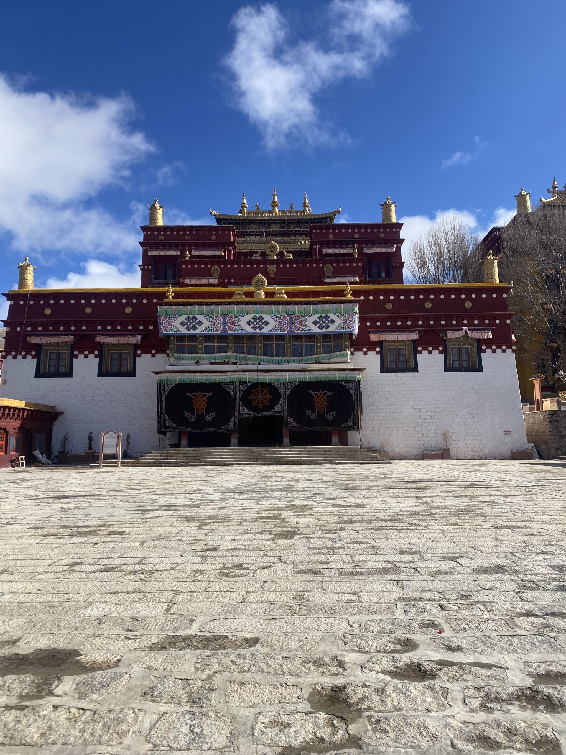 Edifici tibetà de parets blanques i granat sota el cel blau de Litang