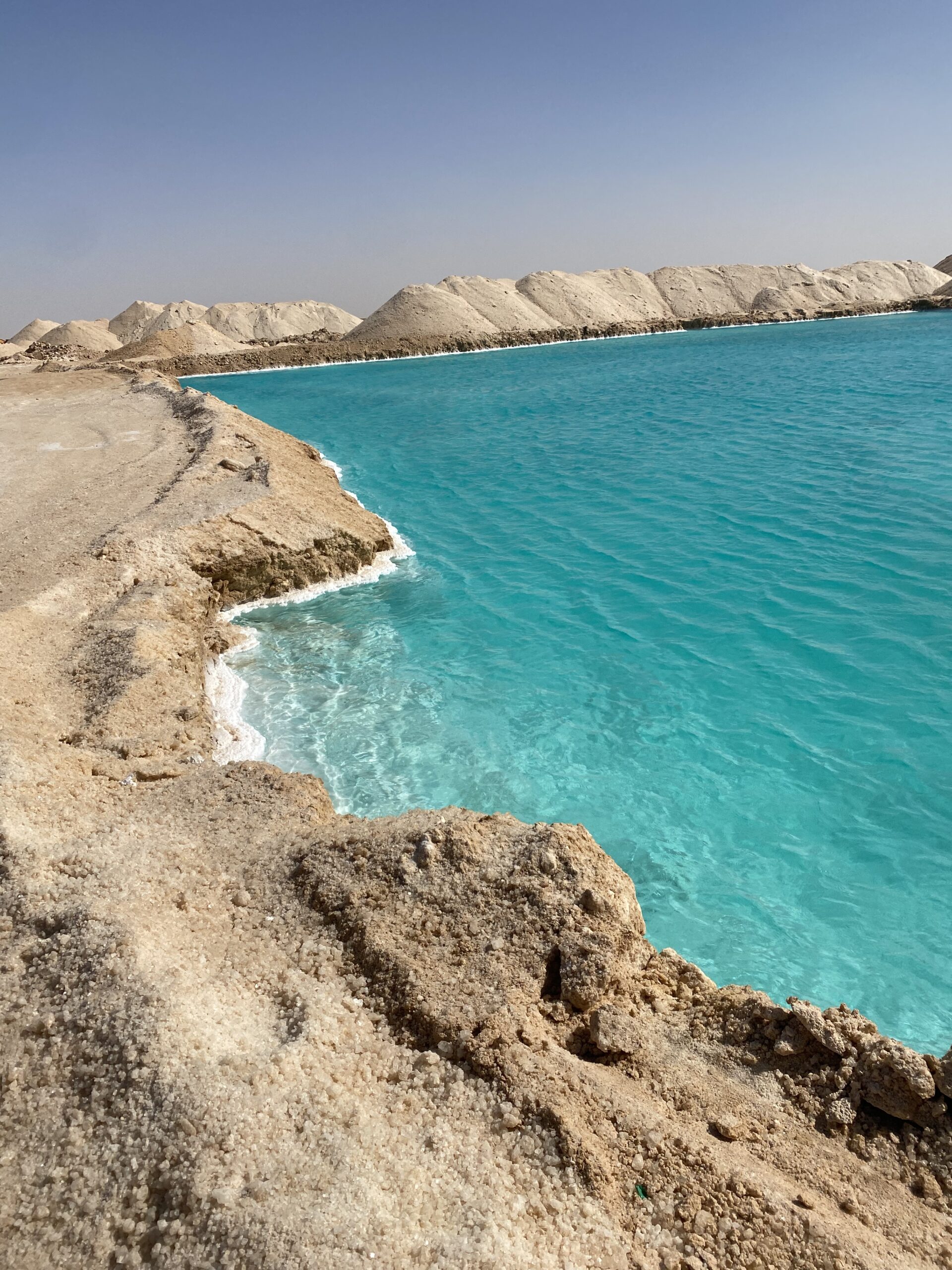 Llac salat de color turquesa amb ribes blanques de sal i el desert al voltant a Siwa