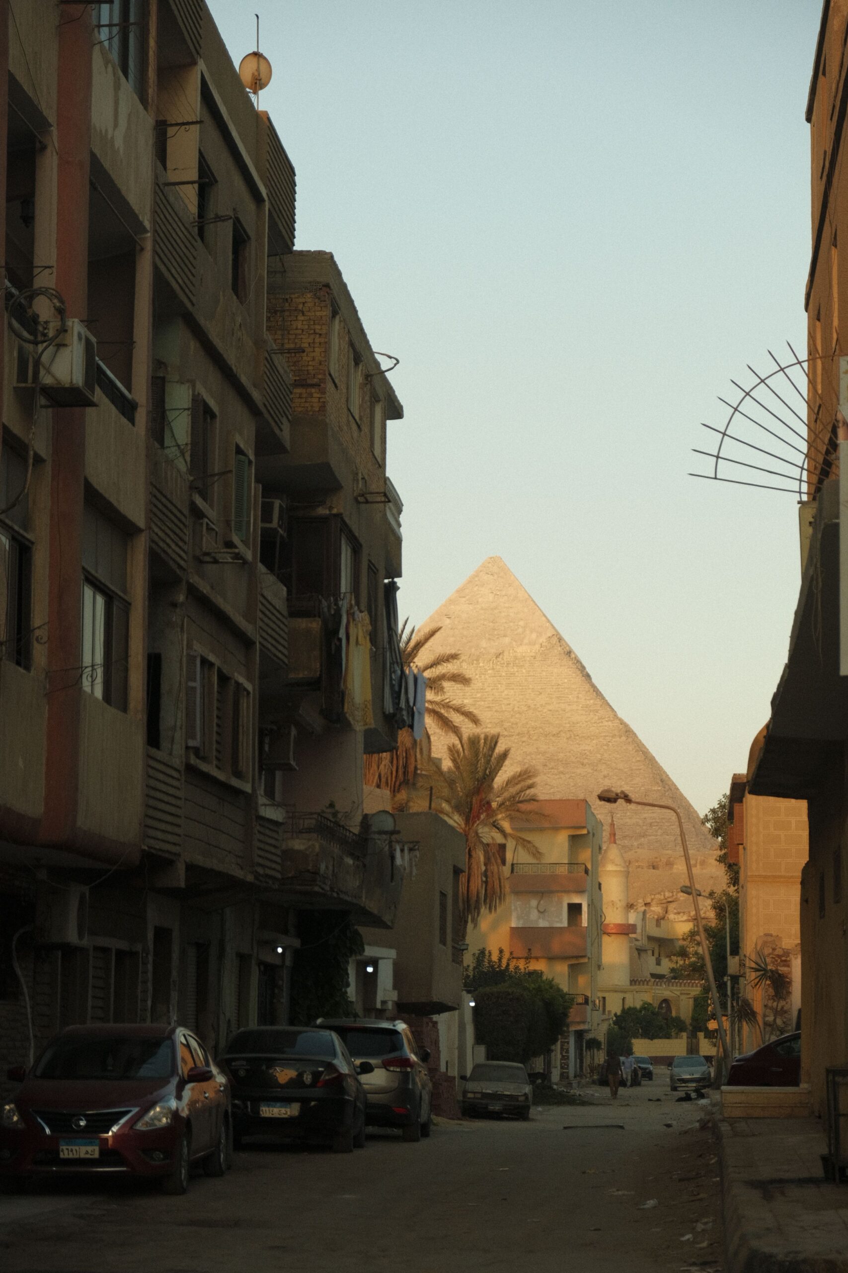 Carrer de Giza amb edificis a banda i banda i una piràmide al fons