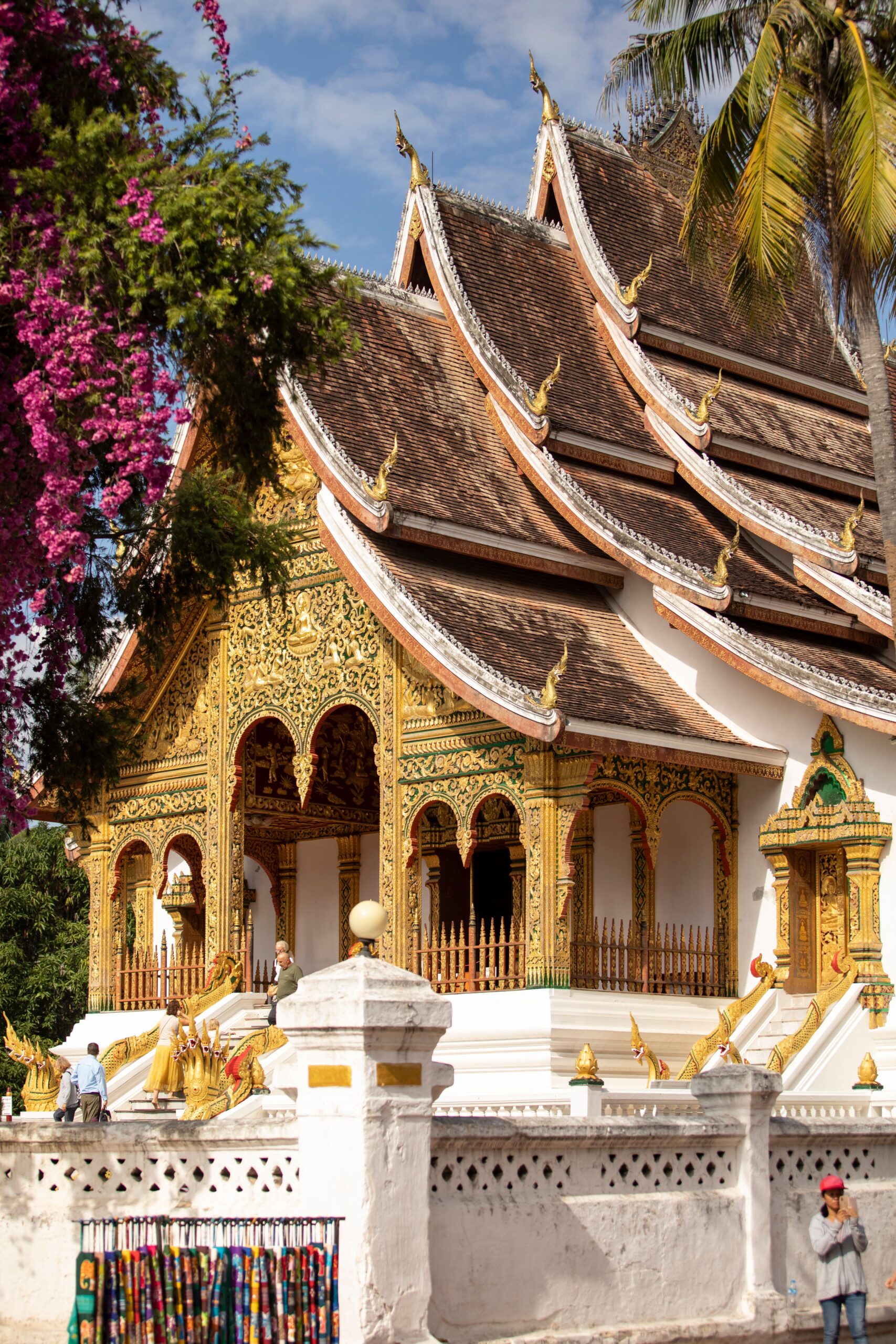 Teulades daurades d'un temple de Luang Prabang envoltades de buguenvíl·lies